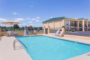 - une piscine avec des chaises et un parasol dans l'établissement Days Inn by Wyndham Byron, à Byron