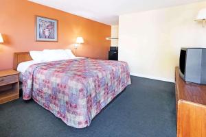 a hotel room with a bed and a flat screen tv at Days Inn by Wyndham Henrietta/Rochester Area in Henrietta