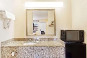 a bathroom with a sink and a mirror and a tv at Days Inn by Wyndham Yazoo City in Yazoo City