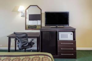 een kamer met een televisie en een bureau met een stoel bij Days Inn by Wyndham Enterprise in Enterprise