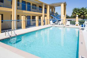 una piscina en un complejo con sillas y un edificio en Days Inn by Wyndham Enterprise, en Enterprise