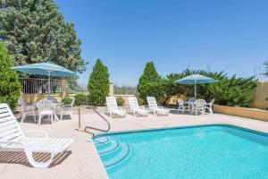 una piscina con sillas y sombrillas y una piscina en Days Inn by Wyndham Deming, en Deming