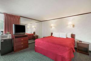 Habitación de hotel con cama roja y TV de pantalla plana. en The Schenectady Inn & Suites en Schenectady