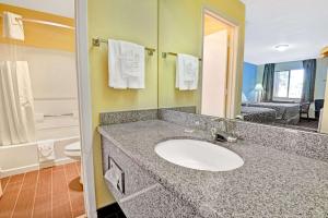 Un baño con lavabo y un espejo grande. en Go2 Inn & Suites By Relianse -Albuquerque, en Albuquerque