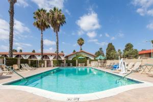 a swimming pool with chairs and palm trees at Days Inn by Wyndham Camarillo - Ventura in Camarillo