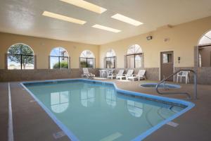 a large swimming pool in a large room with chairs and tables at Days Inn by Wyndham Los Lunas in Los Lunas