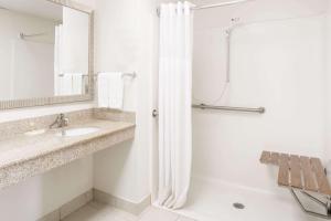 a white bathroom with a shower and a sink at Days Inn by Wyndham Fredericksburg North in Fredericksburg