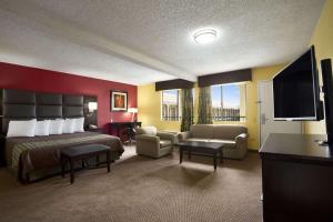 a hotel room with a bed and a flat screen tv at Days Inn by Wyndham Dallas Irving in Irving