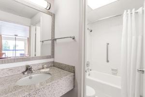 a bathroom with a sink and a shower and a mirror at Days Inn by Wyndham Fredericksburg North in Fredericksburg