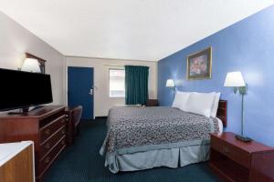 a hotel room with a bed and a flat screen tv at Days Inn by Wyndham Oklahoma City Fairground in Oklahoma City