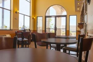un restaurante con mesas, sillas y ventanas en Days Inn by Wyndham Los Lunas, en Los Lunas