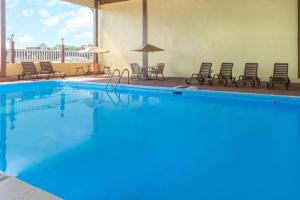 ein großer blauer Pool mit Stühlen und Sonnenschirmen in der Unterkunft Days Inn by Wyndham Waycross in Waycross