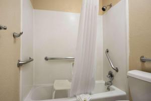 a bathroom with a shower curtain and a toilet at Days Inn by Wyndham Dallas Irving in Irving