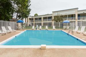 a large swimming pool with chairs and a building at Days Inn by Wyndham Fredericksburg North in Fredericksburg