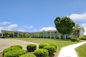 an office building with a tree and bushes at Days Inn by Wyndham Parsippany in Parsippany