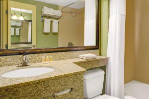 a bathroom with a sink and a toilet and a mirror at Days Inn by Wyndham Cheyenne in Cheyenne