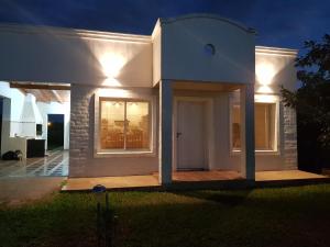Casa blanca con porche delantero por la noche en Rancho Aparte en Ituzaingó