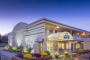 a hotel front of a building with flowers in a parking lot at Days Inn & Suites by Wyndham Dayton North in Dayton