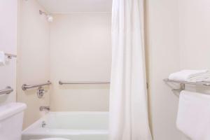 a white bath tub sitting next to a white toilet at Days Inn by Wyndham Owensboro in Owensboro