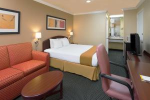 a hotel room with a bed and two chairs and a desk at Days Inn by Wyndham Pinole Berkeley in Pinole