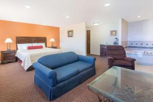 a hotel room with a couch, coffee table and a television at Days Inn by Wyndham Minot in Minot
