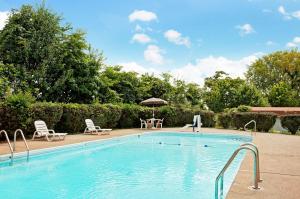 una piscina con sillas, una mesa y una sombrilla en Days Inn by Wyndham Clarksville TN, en Clarksville