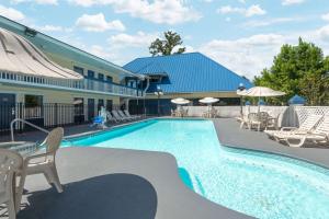 a swimming pool with chairs and umbrellas next to a building at Days Inn by Wyndham Savannah Airport in Savannah