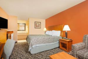 a hotel room with a bed and a chair at Days Inn by Wyndham Centerville in Centerville +6 photos