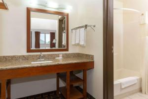 a bathroom with a sink and a mirror and a tub at Days Inn by Wyndham Paxton in Paxton