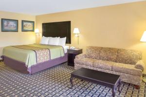 a hotel room with a bed and a couch at Days Inn by Wyndham Andalusia in Andalusia
