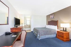 Habitación de hotel con cama, escritorio y TV. en Days Inn by Wyndham Arlington Pentagon en Arlington