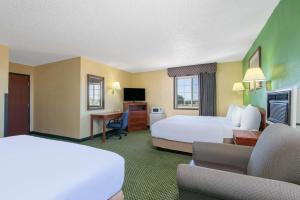 a hotel room with two beds and a desk at Days Inn by Wyndham Great Bend in Great Bend
