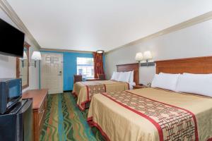 a hotel room with two beds and a flat screen tv at Days Inn by Wyndham Virginia Beach Town Center in Virginia Beach