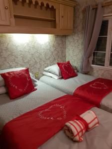 two beds in a bedroom with red and white sheets and pillows at Rooms at Tarrareoch in Bathgate