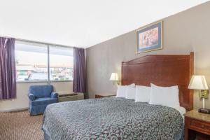 a hotel room with a bed and a chair and a window at Days Inn by Wyndham Arlington Pentagon in Arlington