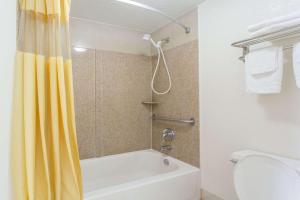 a bathroom with a shower with a yellow shower curtain at Days Inn by Wyndham Virginia Beach Town Center in Virginia Beach