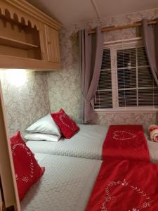 a bedroom with two beds with red pillows and a window at Rooms at Tarrareoch in Bathgate