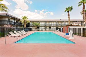 une piscine avec des chaises longues et un hôtel dans l'établissement Days Inn & Suites by Wyndham Needles, à Needles