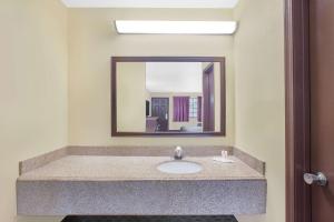 y baño con lavabo y espejo. en Days Inn by Wyndham Fayetteville, en Fayetteville