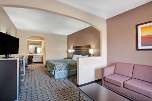 a hotel room with a bed and a couch at Days Inn & Suites by Wyndham Houston North - Spring in Westfield