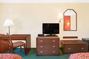 a hotel room with a bedroom with a desk and a television at Days Inn by Wyndham Lincoln in Lincoln