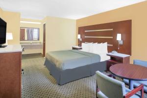 ファイエットビルにあるDays Inn by Wyndham Fayettevilleのベッドとテーブルが備わるホテルルームです。