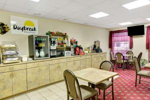 a restaurant with tables and chairs and a counter at Days Inn & Suites by Wyndham Louisville SW in Louisville