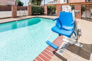 una silla azul sentada junto a una piscina en Days Inn & Suites by Wyndham Dallas, en Dallas