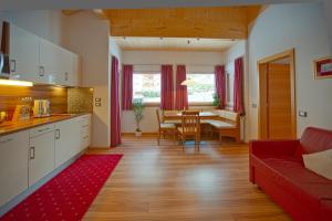 a kitchen and living room with a red couch and a table at Apartaments Galina in Selva di Val Gardena