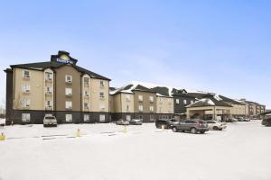 un grand bâtiment avec des voitures garées dans un parking dans l'établissement Days Inn by Wyndham Regina, à Regina