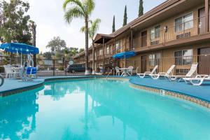 una piscina en un hotel con sillas y sombrillas en Days Inn by Wyndham in San Bernardino, en San Bernardino