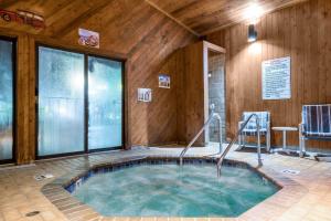 Days Inn by Wyndham Black River Falls - Access to ATV Trail في بلاك ريفير فولز: حوض استحمام ساخن في غرفة مع جدران خشبية