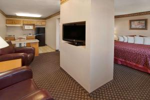 a hotel room with a bed and a flat screen tv at Days Inn & Suites by Wyndham Kokomo in Kokomo
