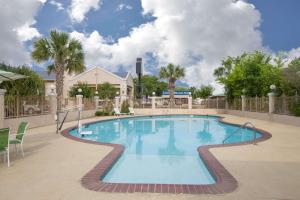 a swimming pool at a resort with palm trees at Days Inn by Wyndham Nacogdoches/SFA University/Downtown in Nacogdoches